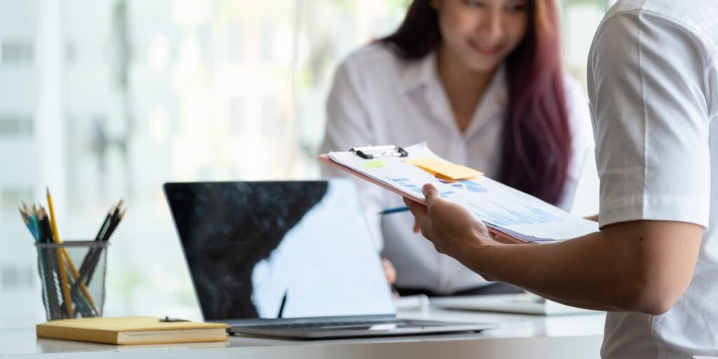 sell-my-house-in-san-diego-meeting Business meeting with real estate agent reviewing contracts and charts helping clients sell my house in San Diego successfully.